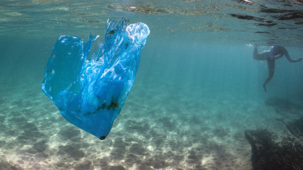 A swimmer near some plastic in the sea